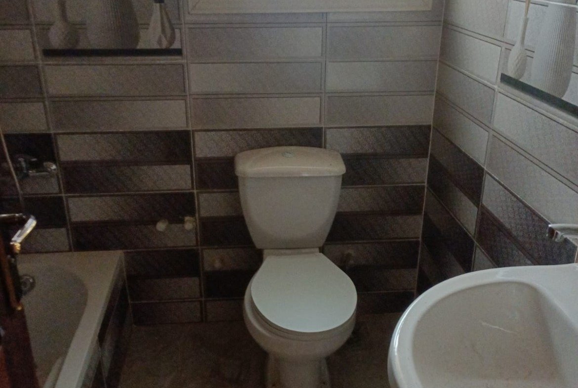 Bathroom with a toilet and a washbasin under a small window - apartment in South Lotus on South 90th Street, New Cairo