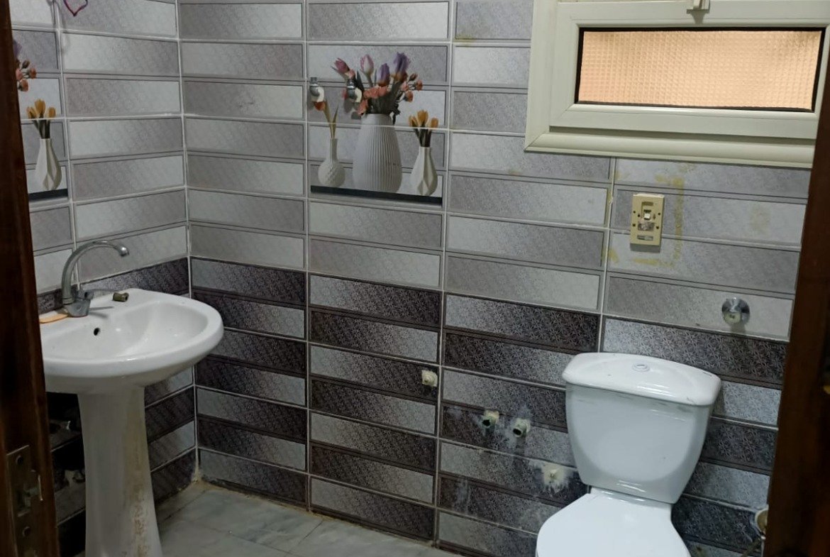 Bathroom with grey and black wall tiles and a pedestal basin - apartment in South Lotus on South 90th Street, New Cairo