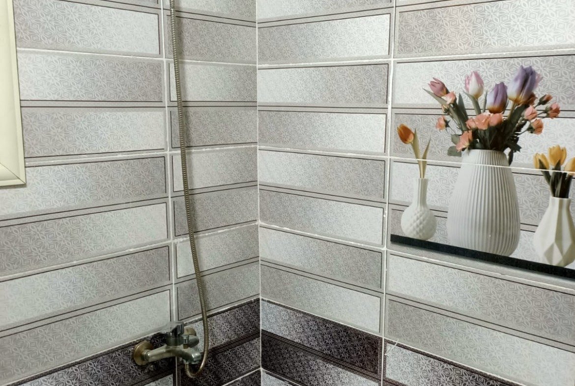 Bathtub with a shower and decorative wall tiles - apartment in South Lotus on South 90th Street, New Cairo