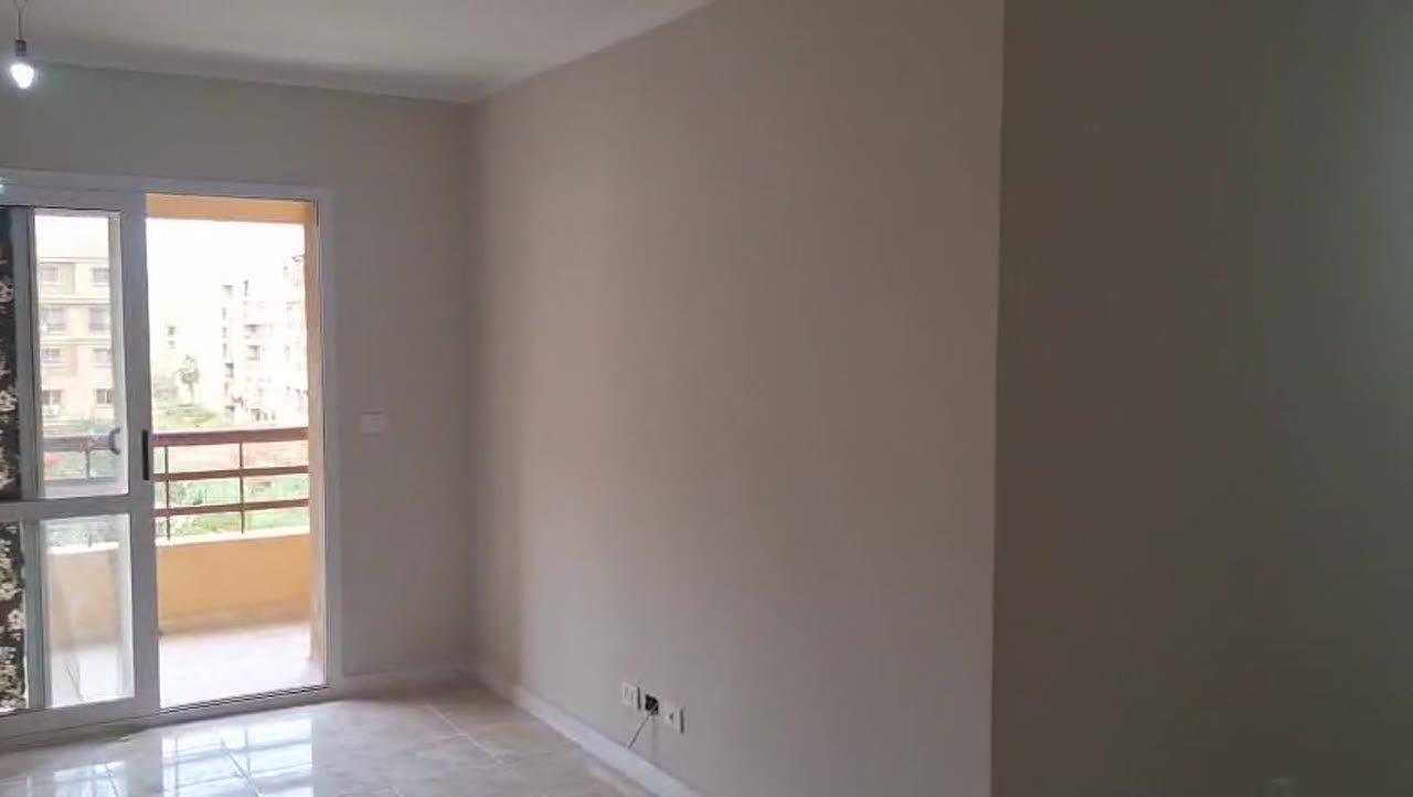 Empty room with a glass balcony door and neighbouring buildings - apartment in Madinaty – 3 Bedrooms 105 sqm Garden View Catch Price, New Cairo