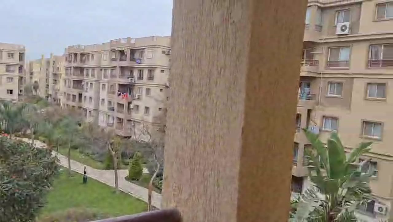 Balcony view of a landscaped courtyard and residential blocks - apartment in Madinaty – 3 Bedrooms 105 sqm Garden View Catch Price, New Cairo