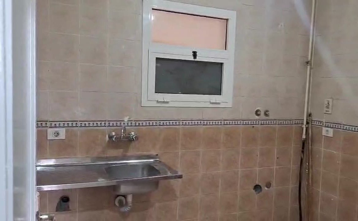Kitchen wall with a steel sink and brown tile border - apartment in Madinaty – 3 Bedrooms 105 sqm Garden View Catch Price, New Cairo