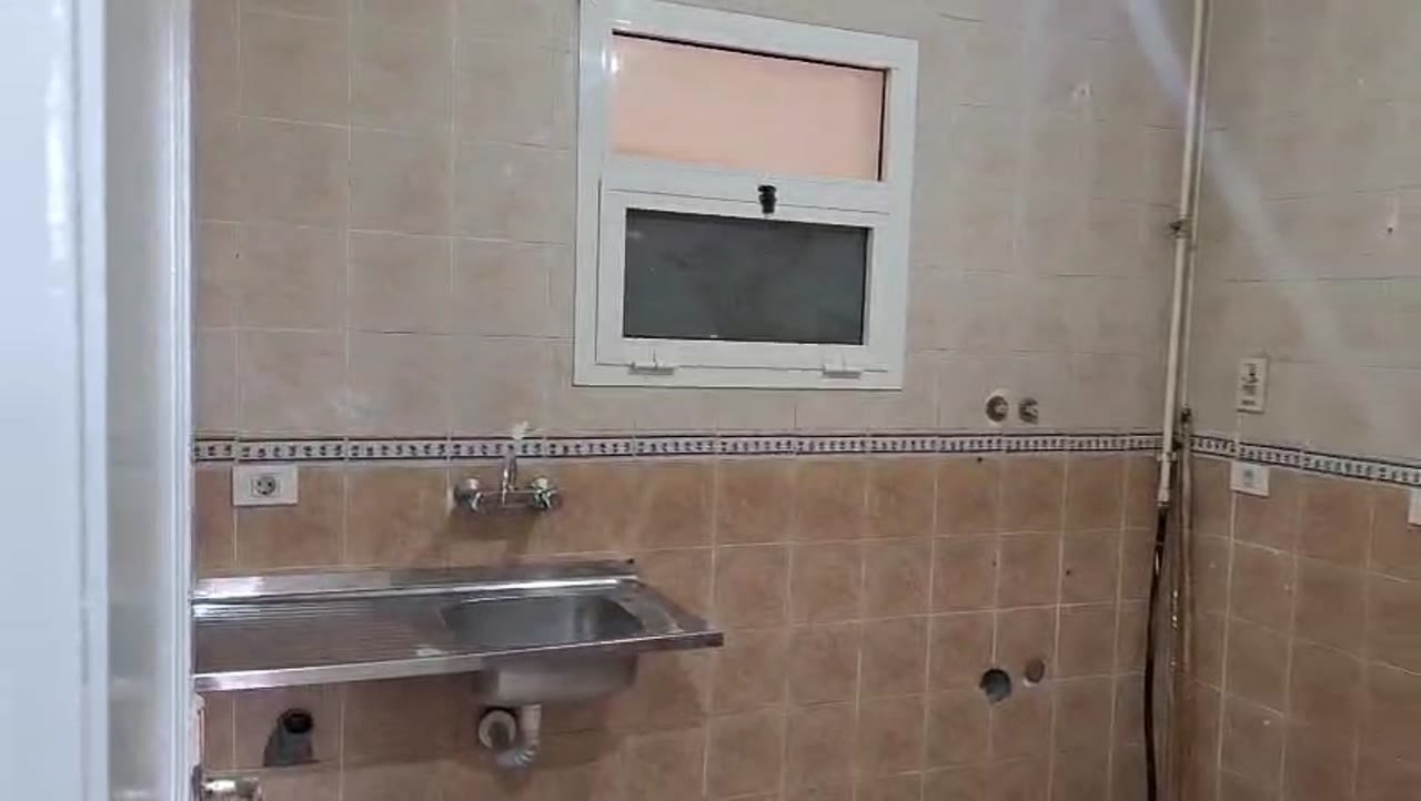 Kitchen wall with a steel sink and brown tile border - apartment in Madinaty – 3 Bedrooms 105 sqm Garden View Catch Price, New Cairo