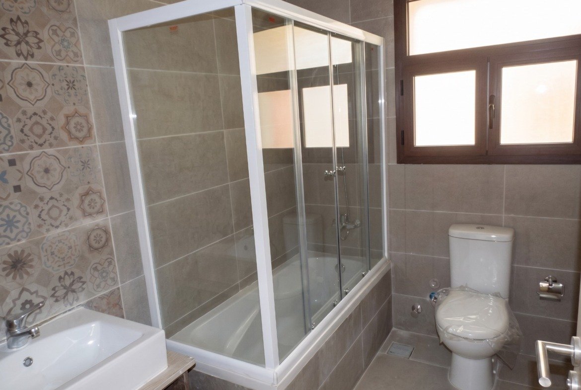 Bathroom with glass shower and bathtub - apartment in Moon Residence, Fifth Square, New Cairo