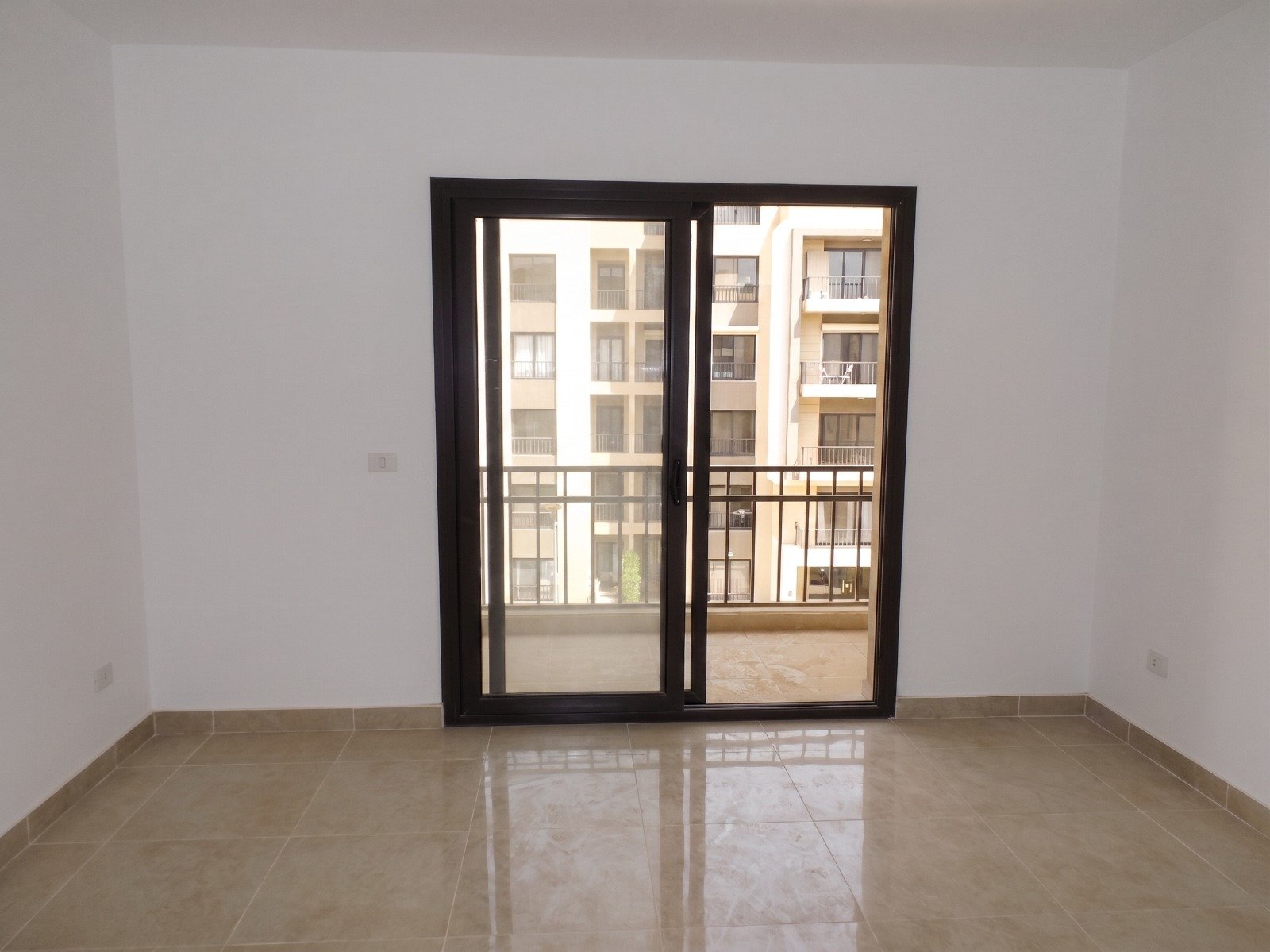 moon-residences-5th-square-bedroom-balcony Empty room with balcony door - apartment in Moon Residence, Fifth Square, New Cairo