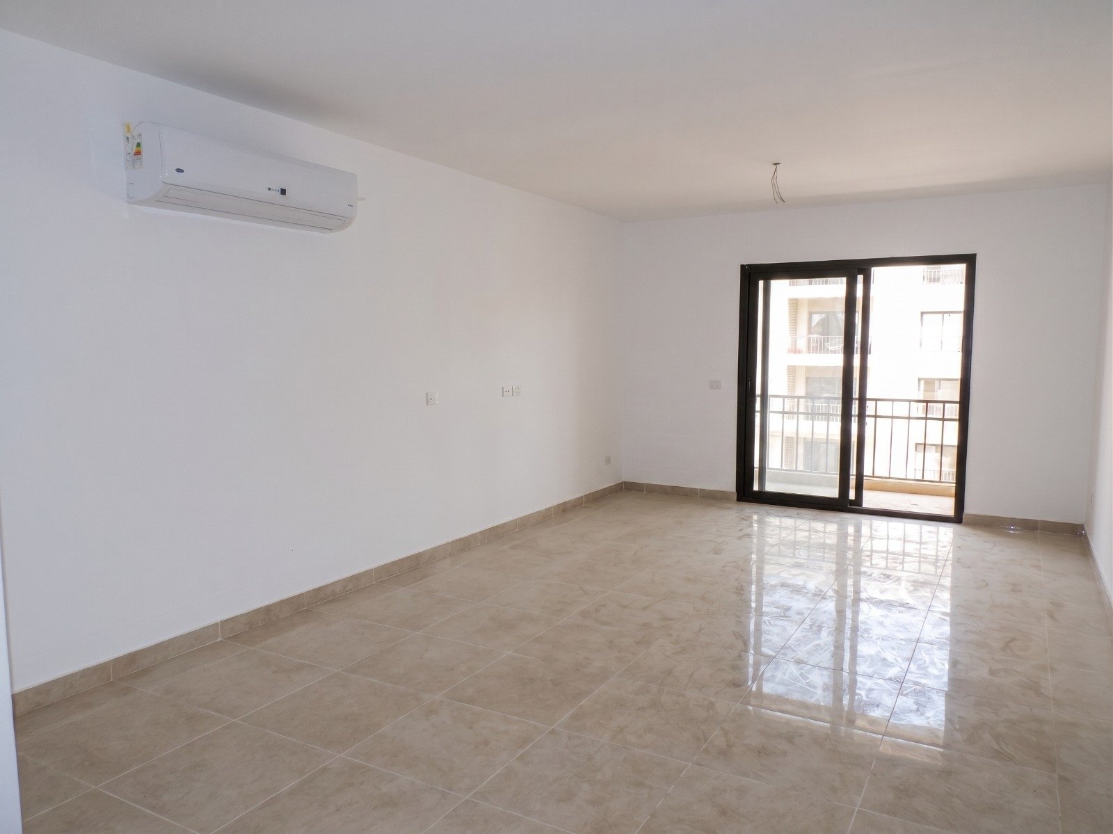 moon-residences-5th-square-living-ac Empty living room with glossy tiles and balcony door - apartment in Moon Residence, Fifth Square, New Cairo