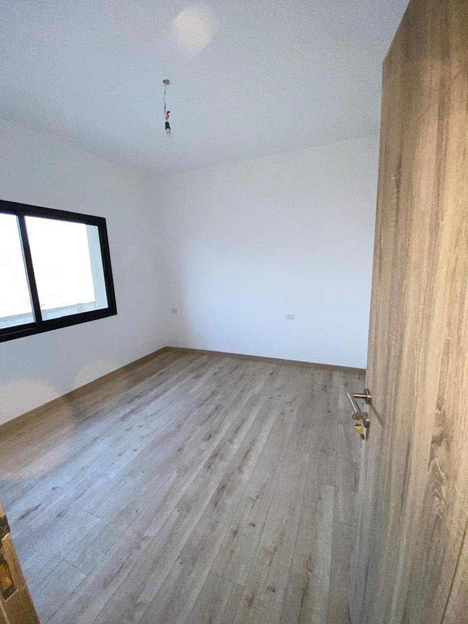 Empty bedroom with wooden floor and window - apartment in Moon Residence, Fifth Square, New Cairo