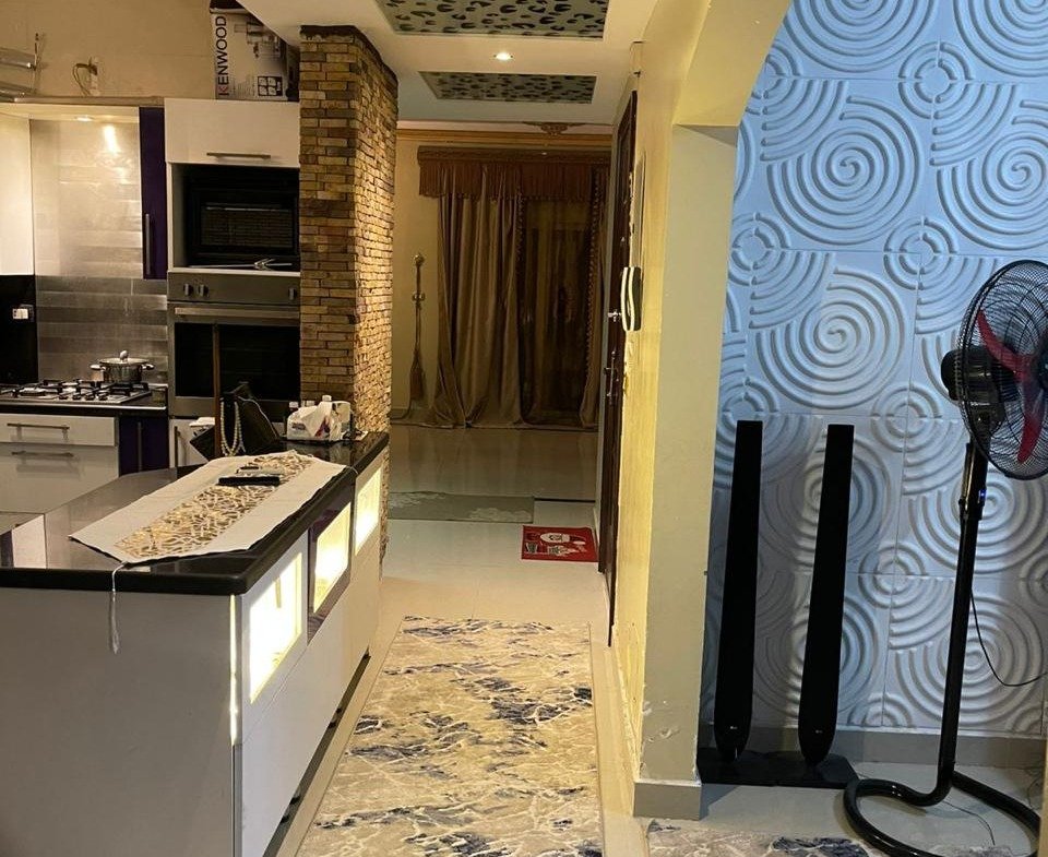 Open kitchen and a patterned hallway rug with a wallpaper accent wall - apartment in South Investors 2, 5th Settlement