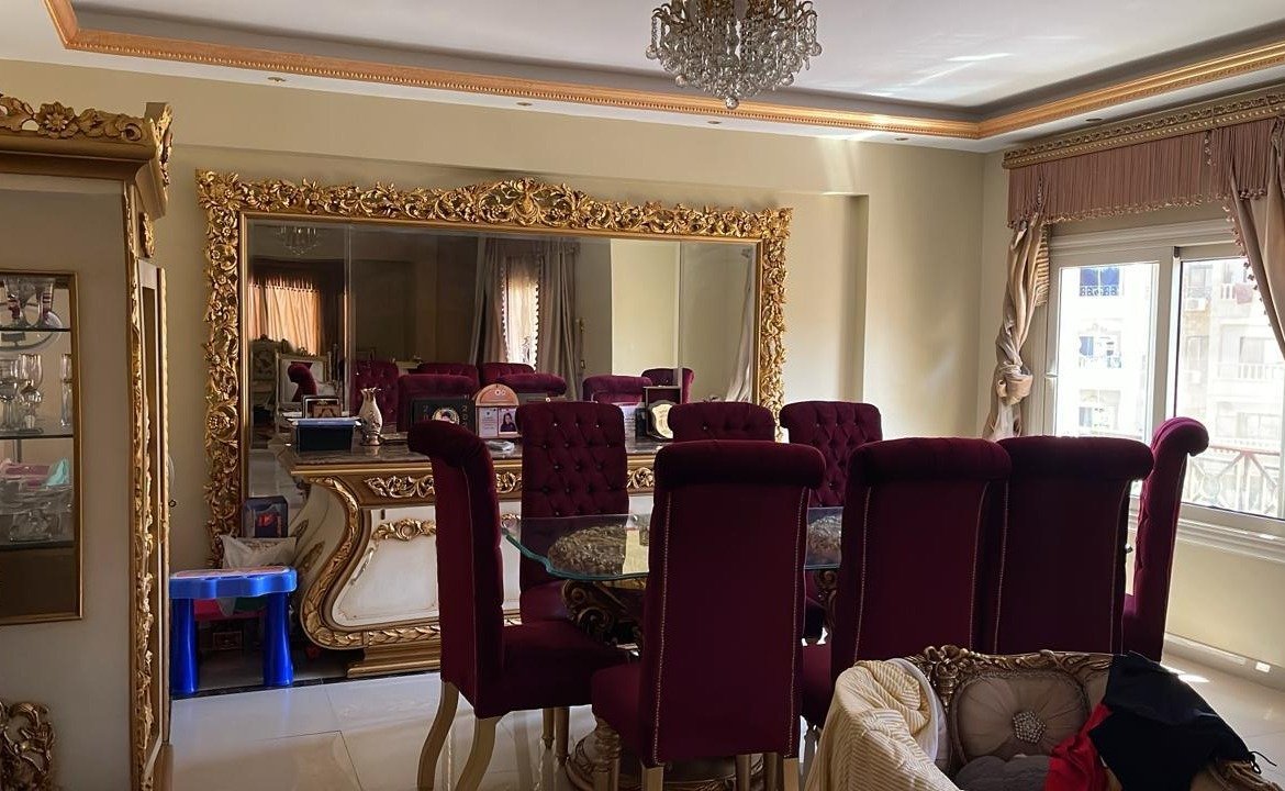 Dining room with burgundy chairs, a gilded mirror and a chandelier - apartment in South Investors 2, 5th Settlement