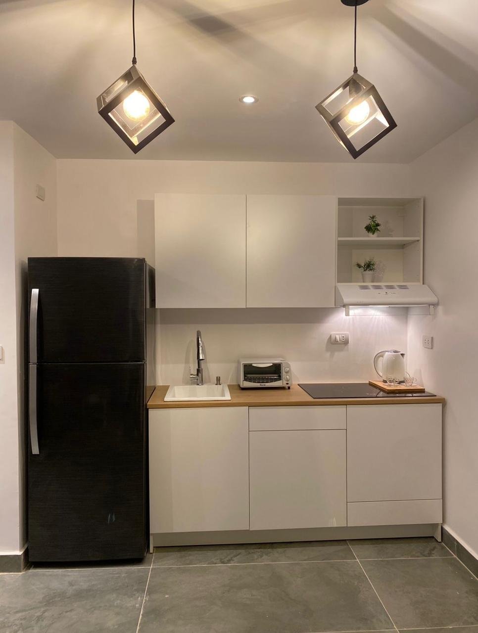 mvic525-u15 White kitchenette with two pendant lights and a black fridge - apartment in Mountain View iCity, New Cairo