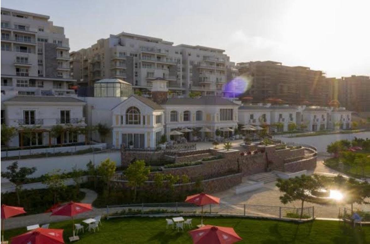 mvic525-u19 Clubhouse and landscaped lawn at sunset with red umbrellas - apartment in Mountain View iCity, New Cairo