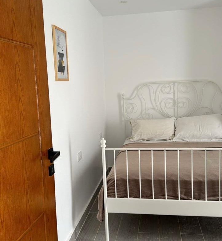 White metal bed beside an orange wooden door - apartment in Mountain View iCity, New Cairo