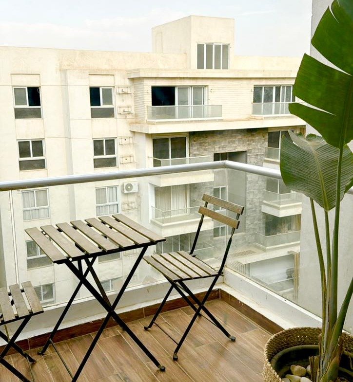 Balcony with a folding table and a large plant - apartment in Mountain View iCity, New Cairo