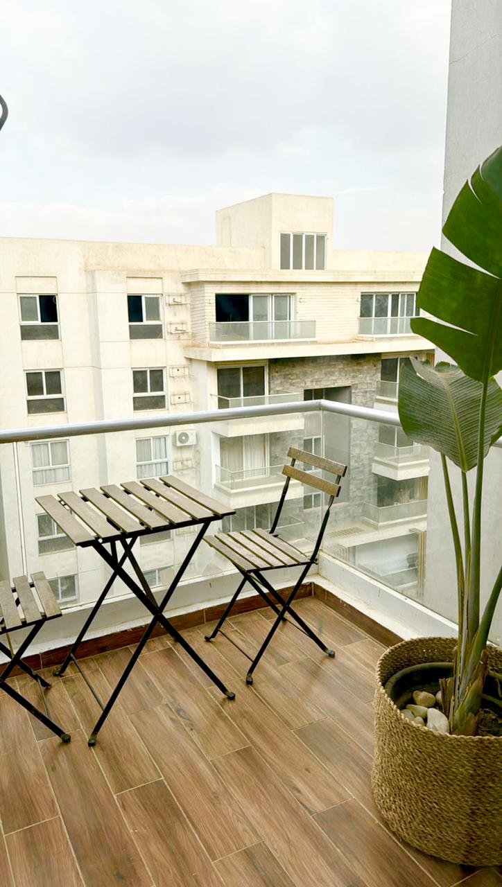 mvic525-u5 Balcony with a folding table and a large plant - apartment in Mountain View iCity, New Cairo