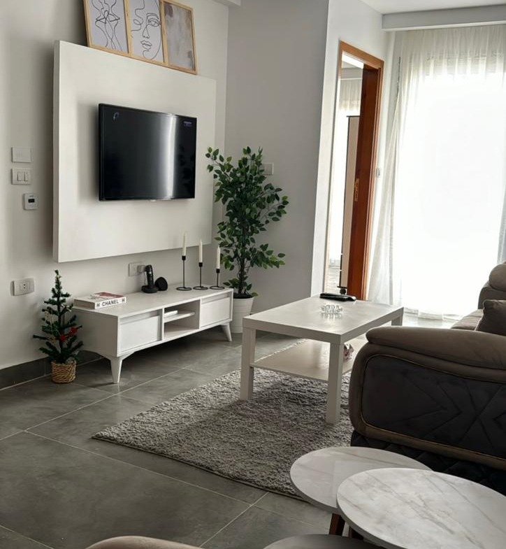 Living room with a wall TV unit and round tables - apartment in Mountain View iCity, New Cairo