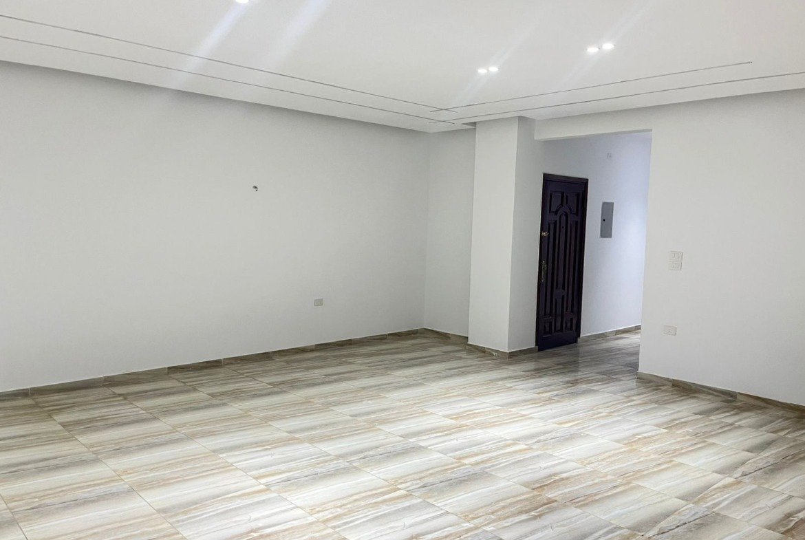 Empty room with white walls and a dark door at the back - unit in Marassi