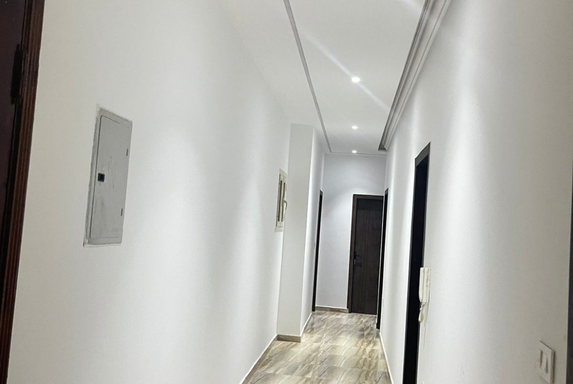 Long hallway with a marble-look floor and dark doors - unit in Marassi