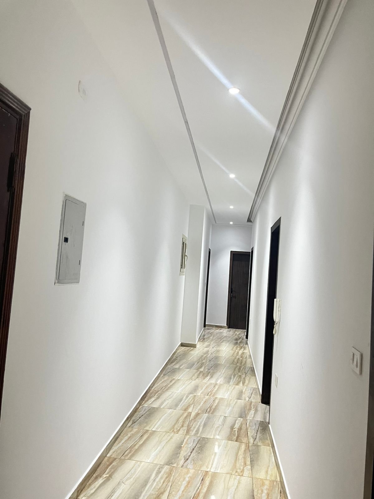 Long hallway with a marble-look floor and dark doors - unit in Marassi