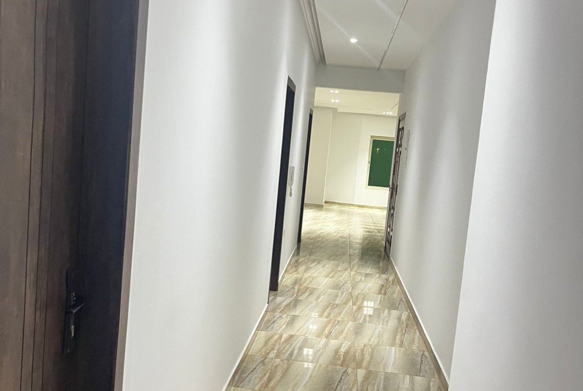 Corridor with a wooden door and a bright plank-look floor - unit in Marassi