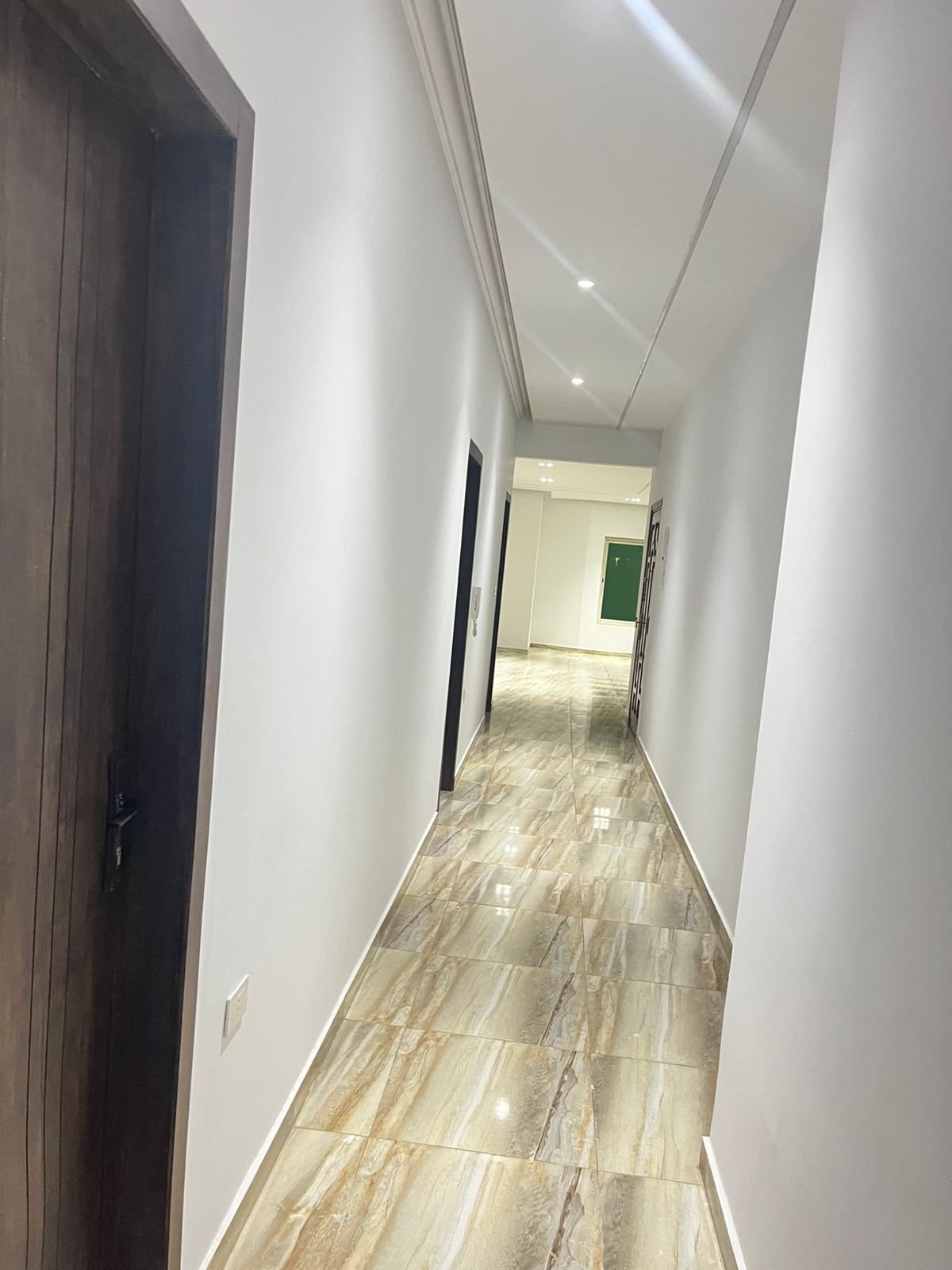Corridor with a wooden door and a bright plank-look floor - unit in Marassi