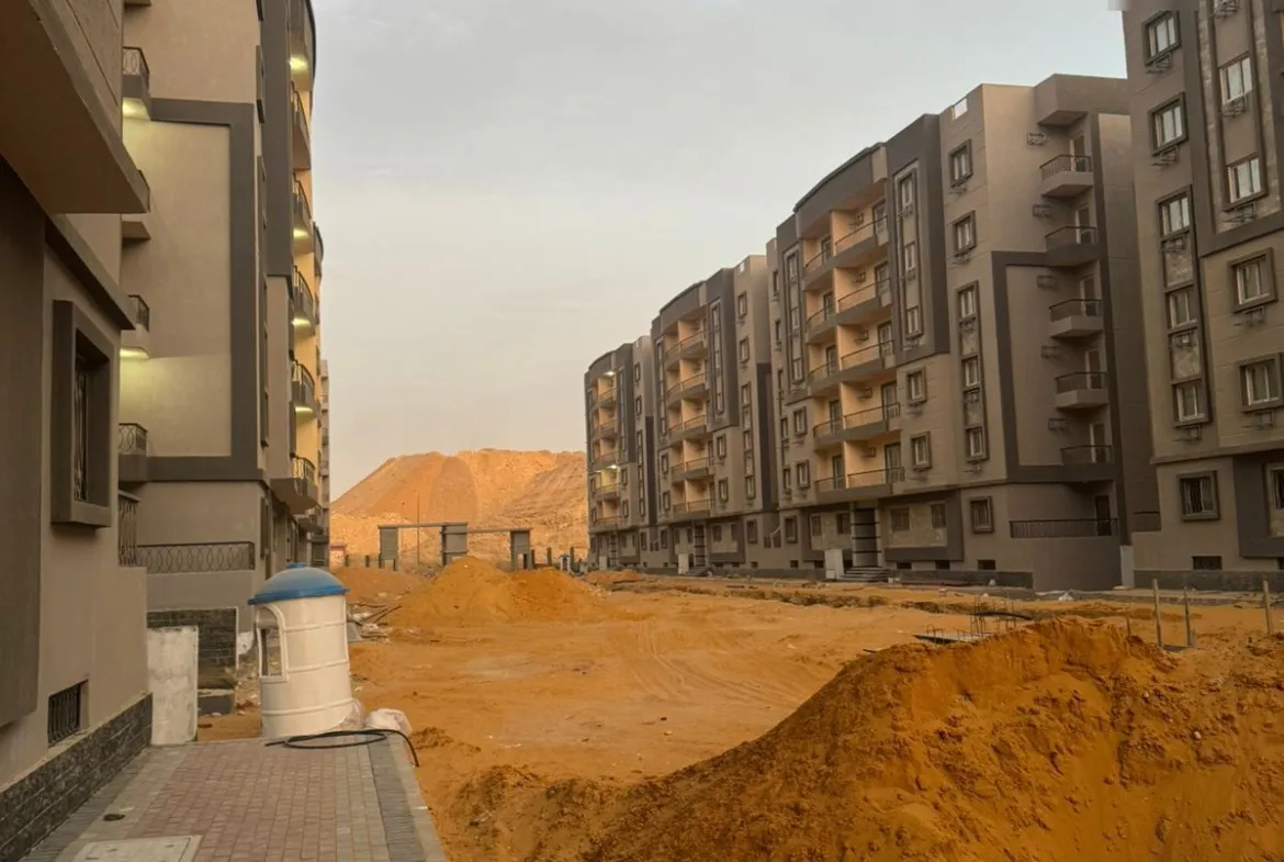 بلوكات سكنية وتل رمل بجوار طريق جديد وقت الغروب - شقة في نزهة الأندلس، التجمع الخامس