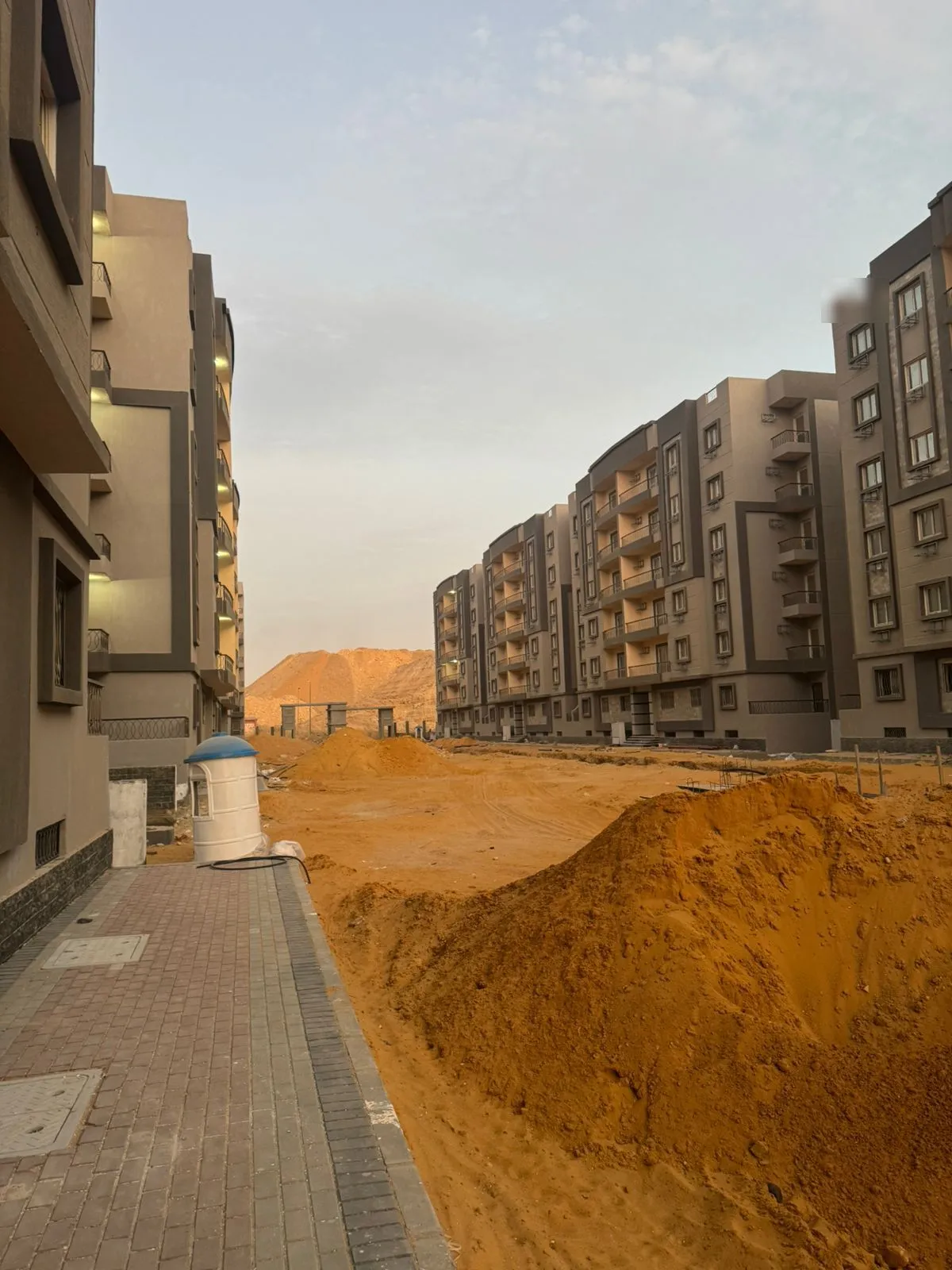 بلوكات سكنية وتل رمل بجوار طريق جديد وقت الغروب - شقة في نزهة الأندلس، التجمع الخامس