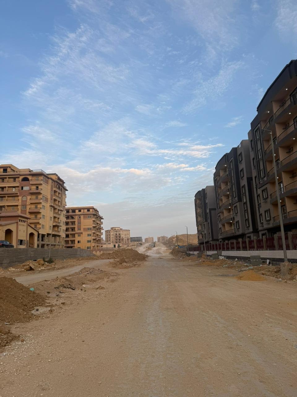 طريق ترابي بين مبانٍ سكنية تحت سماء زرقاء - شقة في نزهة الأندلس، التجمع الخامس