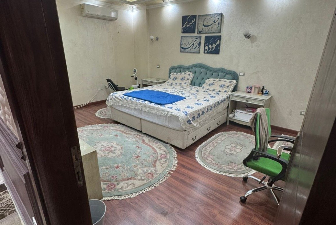 Bedroom with a floral bed cover and a wooden floor - duplex in One Piece, New Cairo