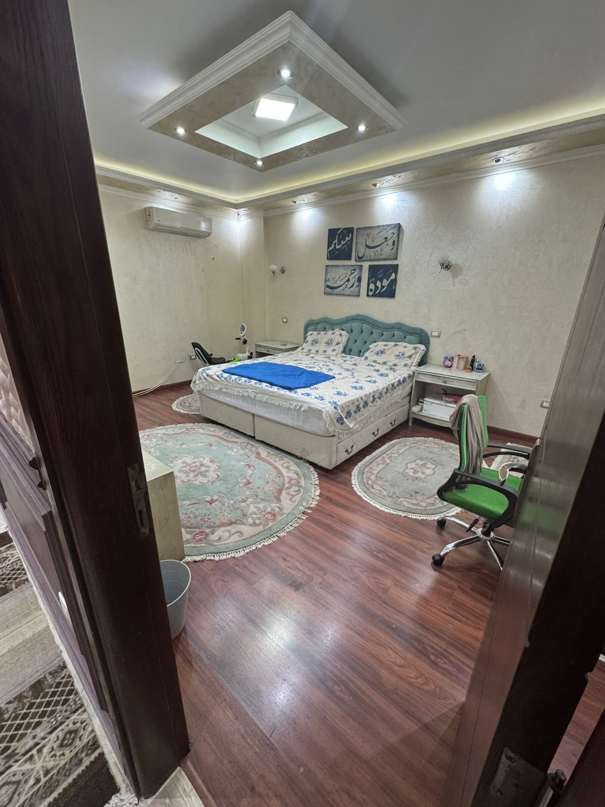 Bedroom with a floral bed cover and a wooden floor - duplex in One Piece, New Cairo