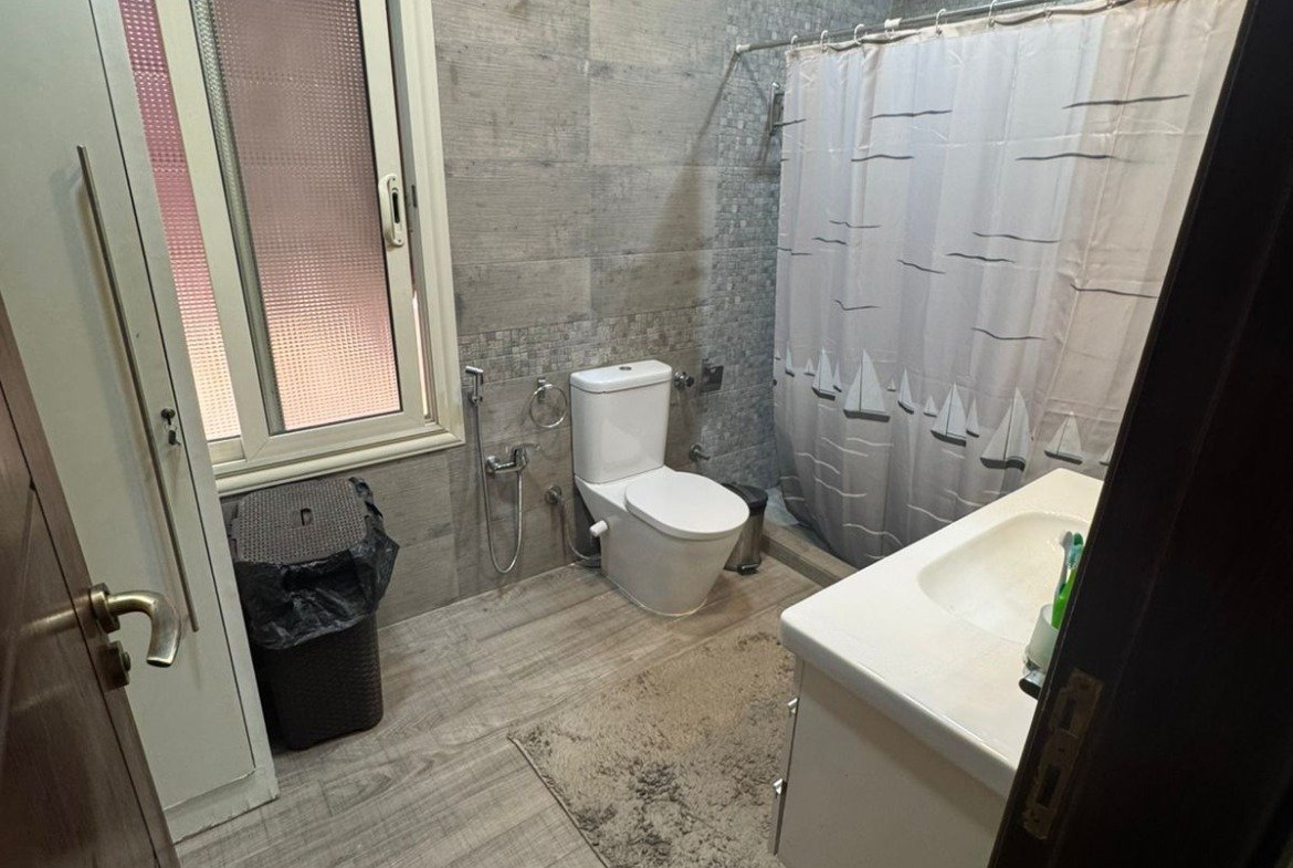 Bathroom with a toilet, a vanity and a curtain - duplex in One Piece, New Cairo