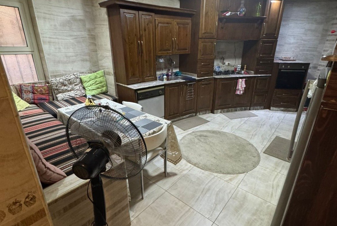 Open kitchen and sitting area with a standing fan - duplex in One Piece, New Cairo