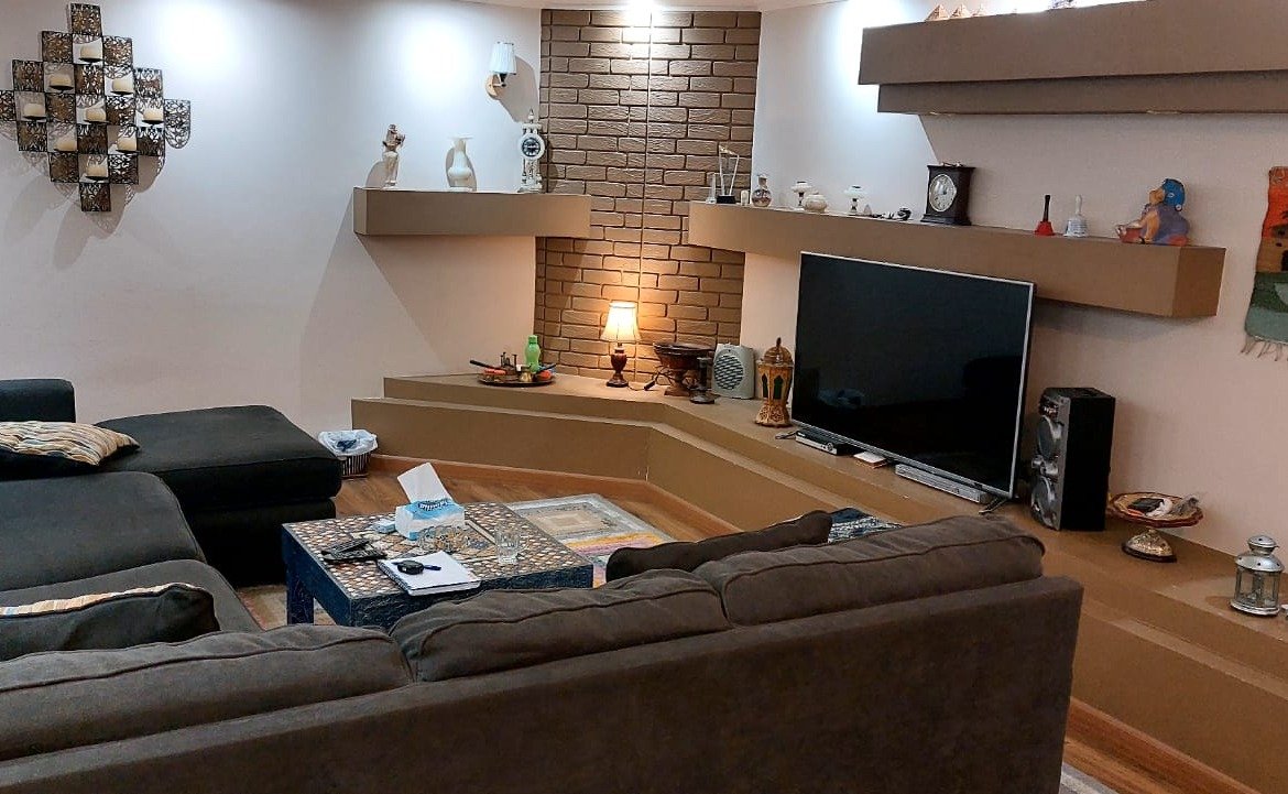 Living room with a grey L-shaped sofa and a TV wall - duplex in One Piece, New Cairo