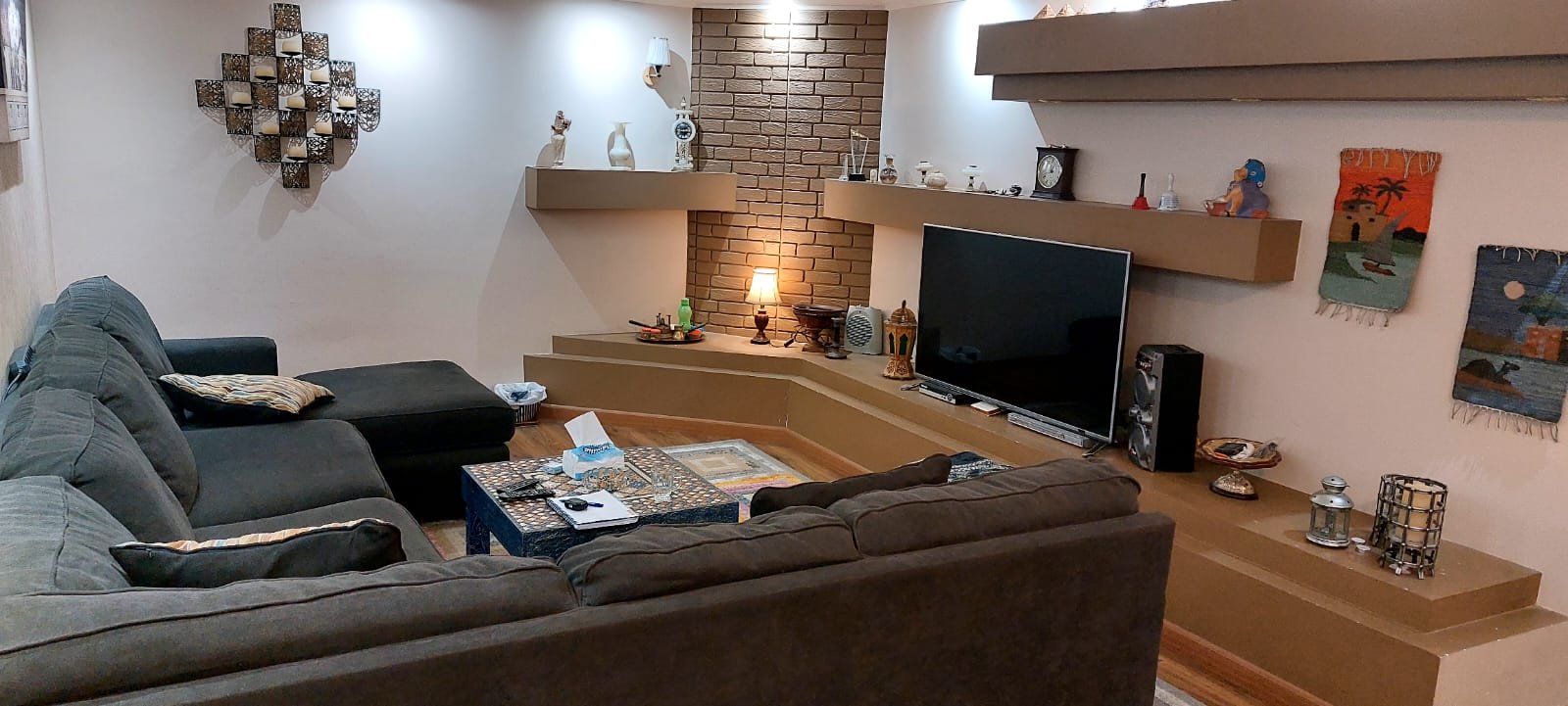 Living room with a grey L-shaped sofa and a TV wall - duplex in One Piece, New Cairo