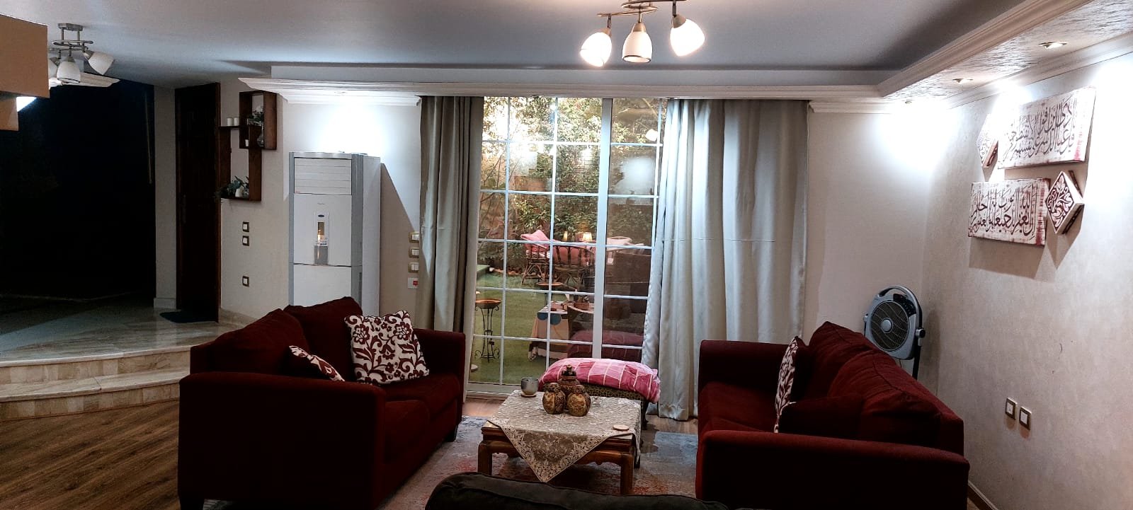 Living room with red sofas and garden-view curtains - duplex in One Piece, New Cairo