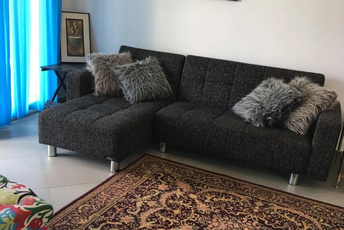 Living room with a black sofa and a patterned rug - apartment in Park View, New Cairo