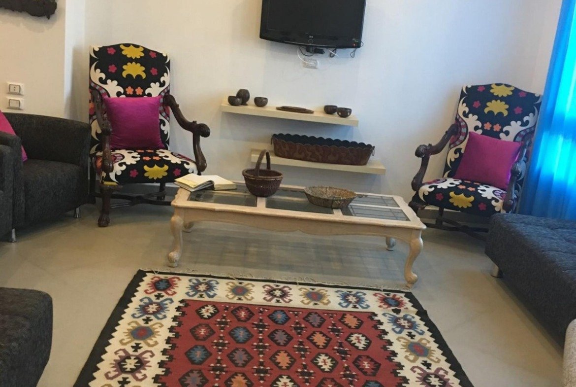 Living room with a red kilim rug and wall TV - apartment in Park View, New Cairo