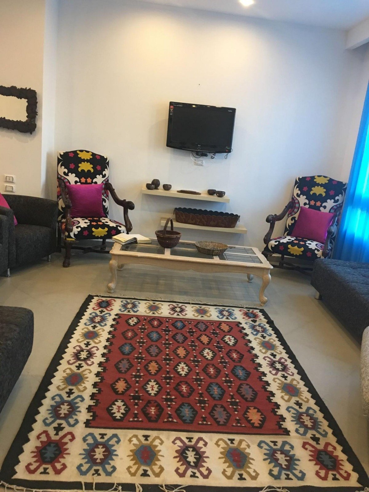 Living room with a red kilim rug and wall TV - apartment in Park View, New Cairo