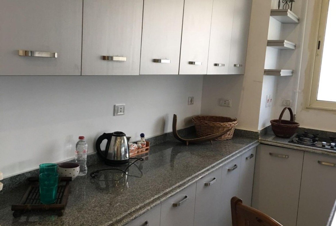 Kitchen with white cabinets and a granite counter - apartment in Park View, New Cairo