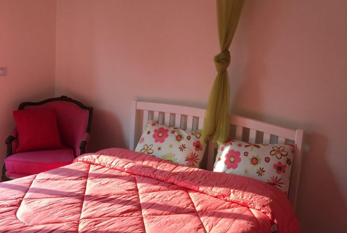 Bedroom with a pink quilted bedspread and a mosquito net - apartment in Park View, New Cairo