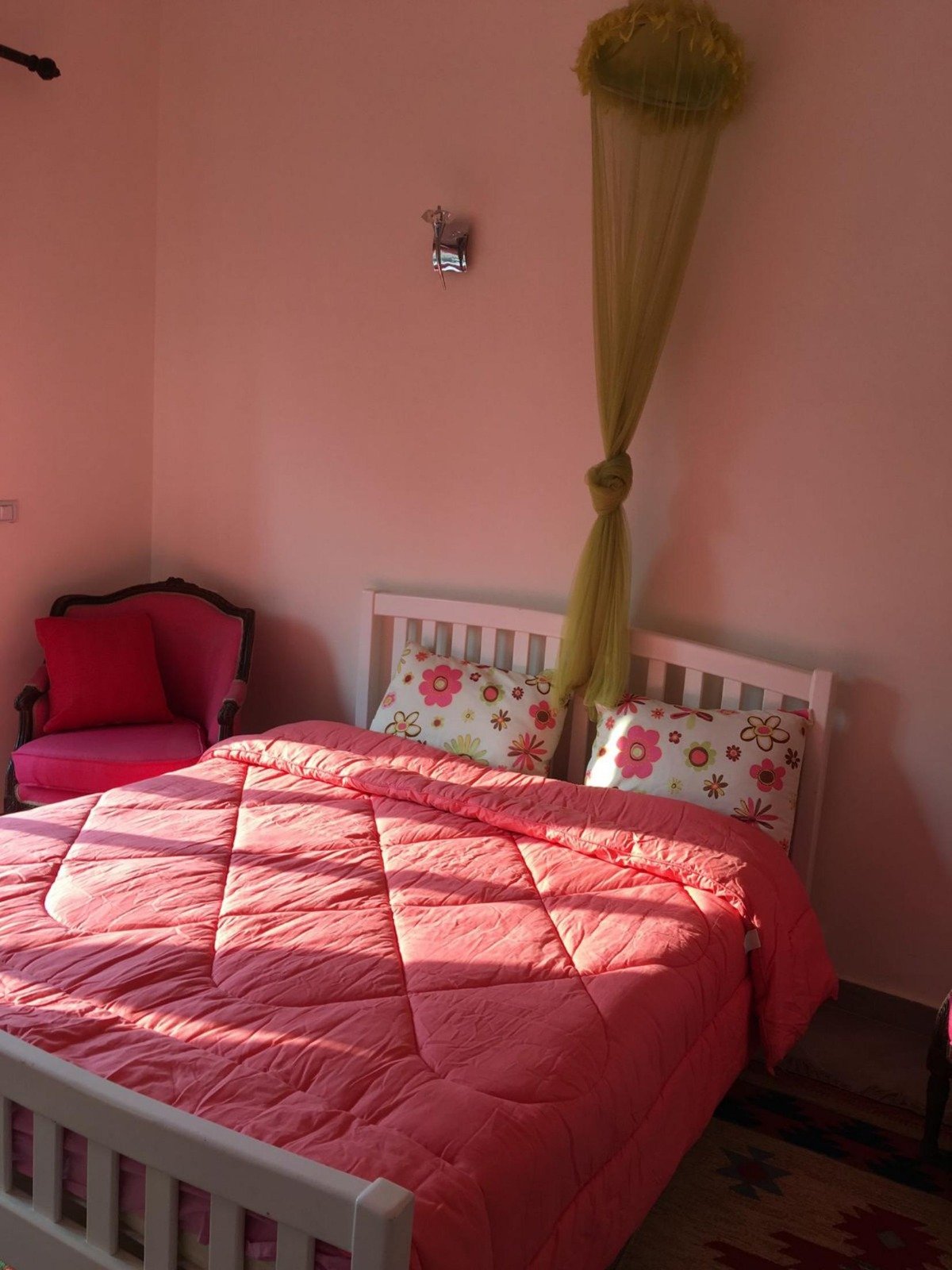 Bedroom with a pink quilted bedspread and a mosquito net - apartment in Park View, New Cairo