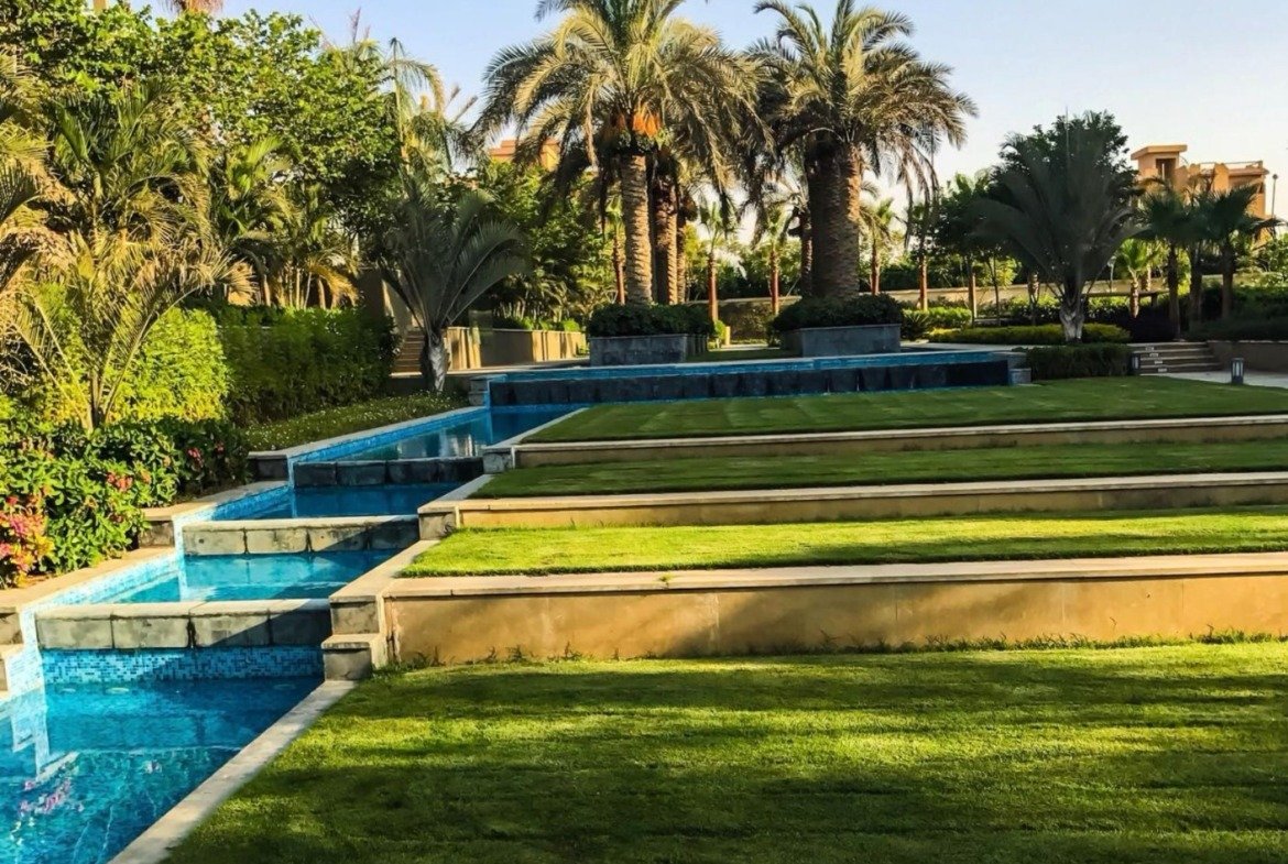 Terraced water feature with lawn steps and palms - apartment in Park View, New Cairo