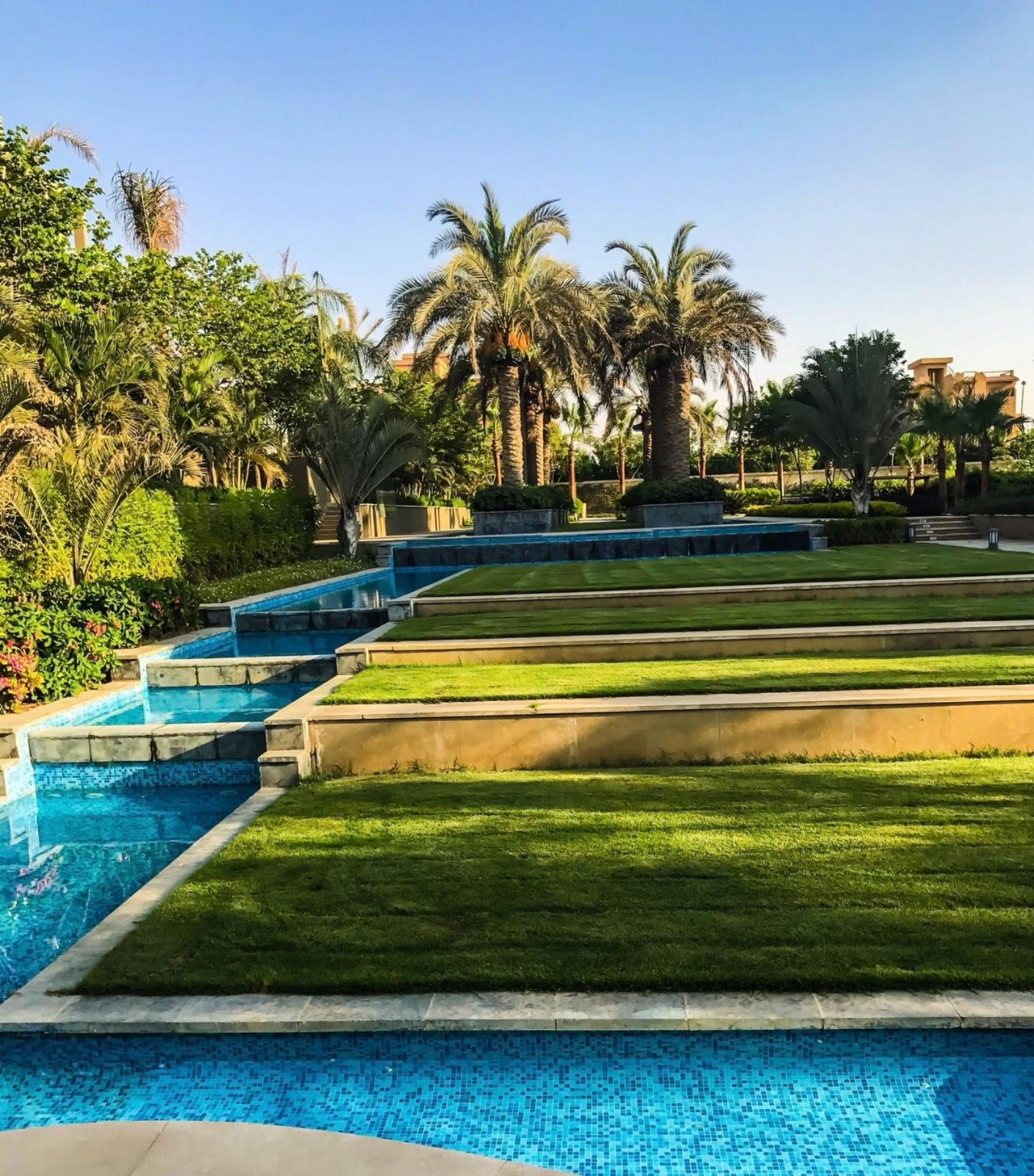 Terraced water feature with lawn steps and palms - apartment in Park View, New Cairo