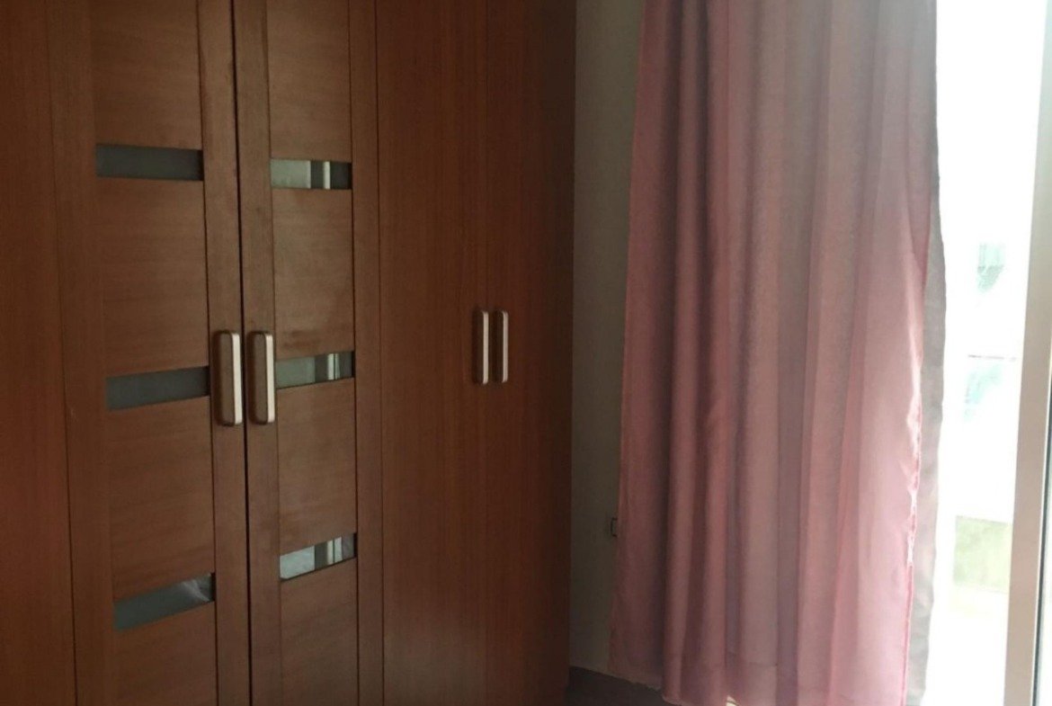 Built-in wooden wardrobe beside a pink bed - apartment in Park View, New Cairo