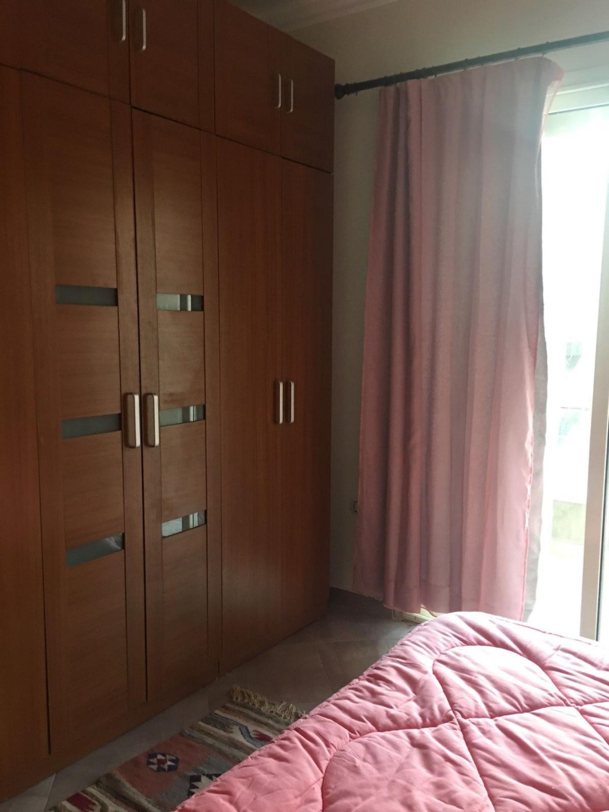 Built-in wooden wardrobe beside a pink bed - apartment in Park View, New Cairo