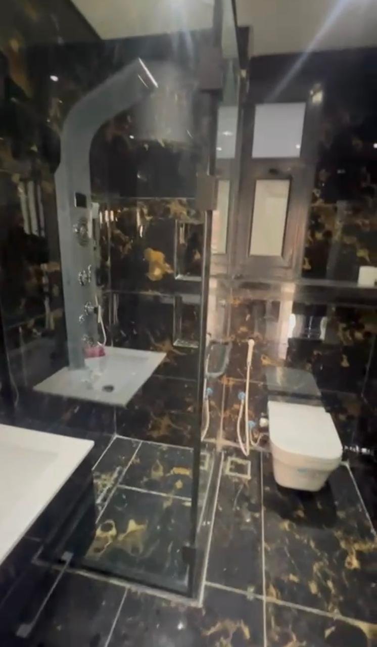 Bathroom with gold-veined black marble and a glass shower - apartment in El Patio Oro, New Cairo