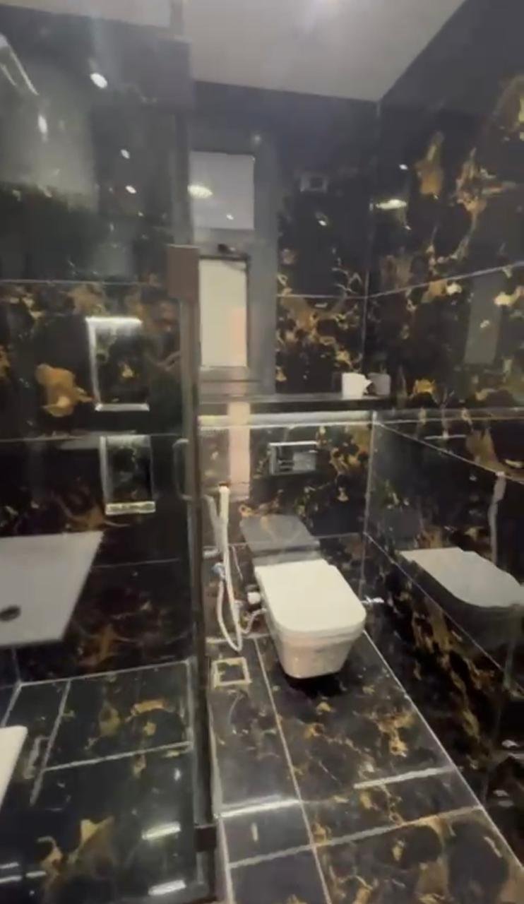 Bathroom with black and gold marble walls and a wall-hung toilet - apartment in El Patio Oro, New Cairo