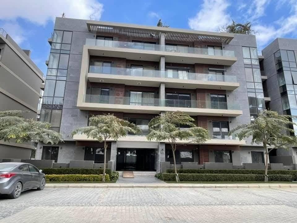 Building facade with balconies and palm trees at the entrance - apartment in El Patio Oro, New Cairo