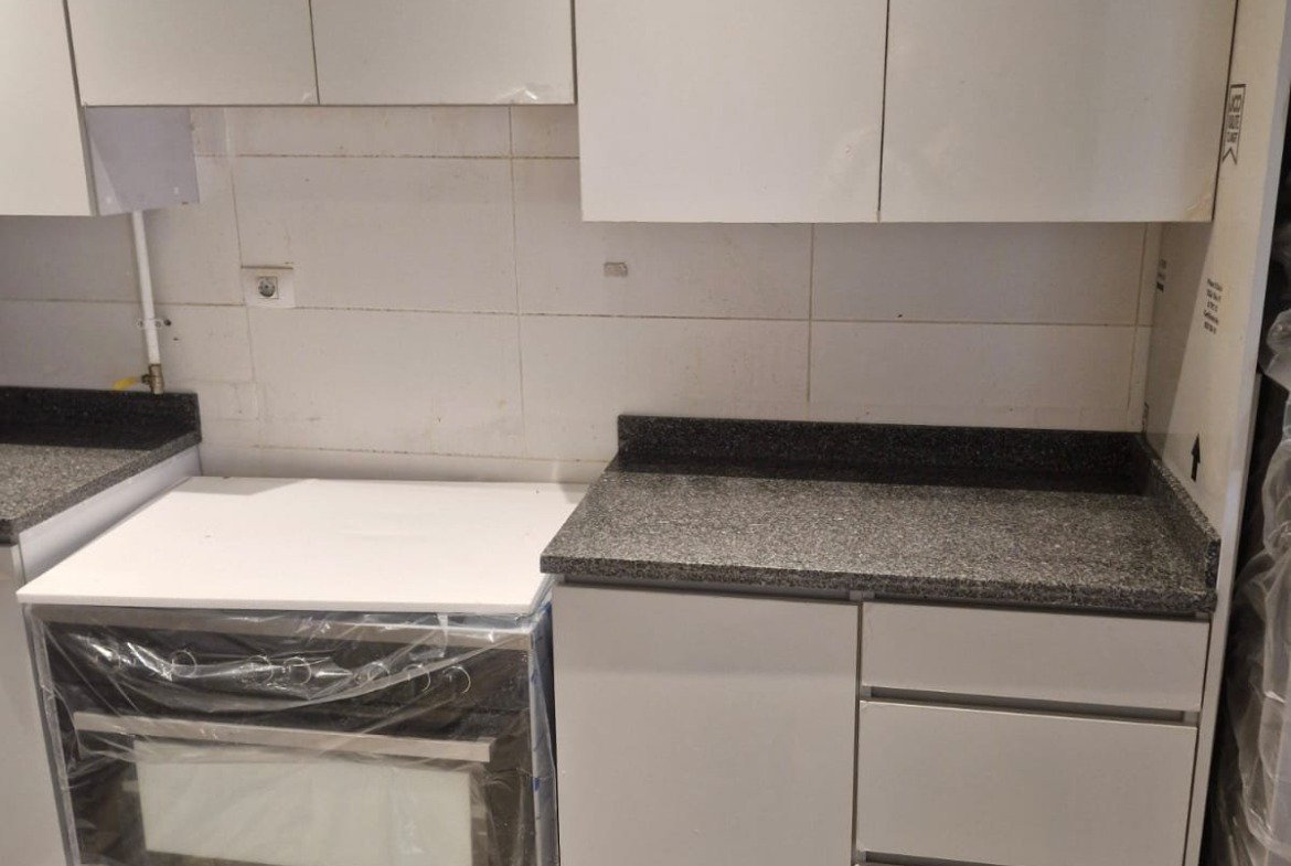 Small kitchen with white cabinets and a built-in cooker - penthouse in Cairo Festival City, New Cairo