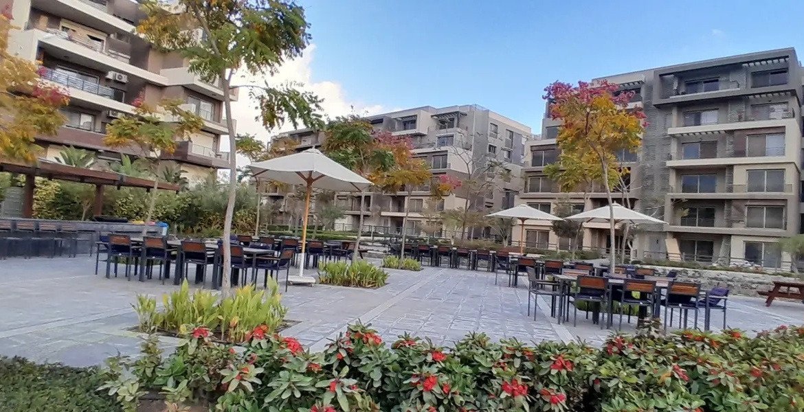 Outdoor dining area in a landscaped compound plaza - apartment in Palm Hills, New Cairo