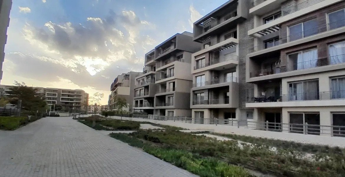 Evening light over modern apartment blocks and a garden path - apartment in Palm Hills, New Cairo